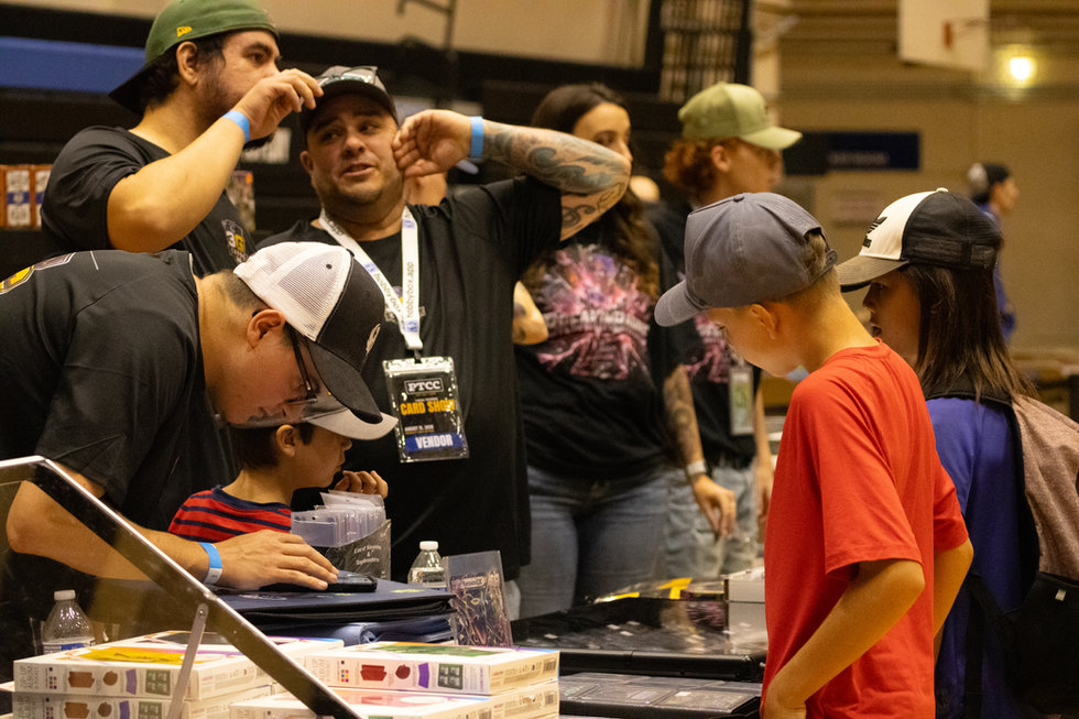 A vendor and younger attendees looking at cards together at the PTCC show